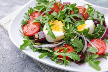 Tasty salad with arugula, vegetables, egg and seeds on grey table, closeup