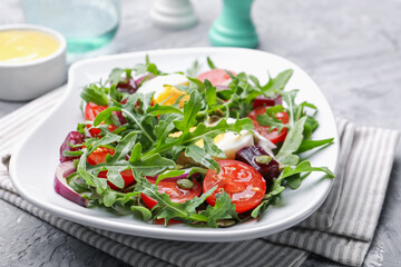 Tasty salad with arugula, vegetables, egg and seeds on grey table, closeup