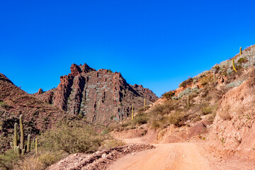 Fototapeta premium Vast and rugged desert landscape with a dusty road leading into the distant mountains of the Argentine Andes.