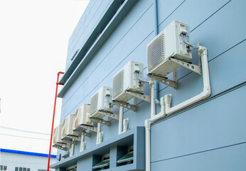 Condenser unit or compressor outside home or residential building. Unit of central air conditioner AC or heating ventilation air conditioning system HVAC. Electric fan and refrigerant pump inside.