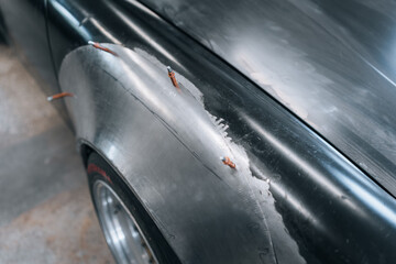 Photo of classic car under restoration – stripped body, wide fenders and vintage rims captured in...