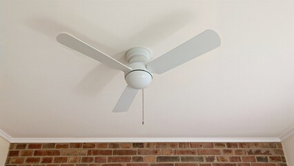 Rotating white ceiling fan against a white ceiling and brick wall backdrop