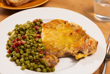 Fried boneless skinless chicken leg with green peas for garnish on plate