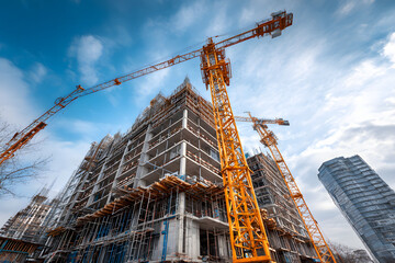 Construction site showcases a towering crane operating above a multi-story building under development in a bright, clear sky