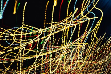 The image is a blurry, colorful, and dynamic representation of light. The yellow and red streaks are moving and overlapping, creating a sense of motion and energy. Scene is vibrant and lively