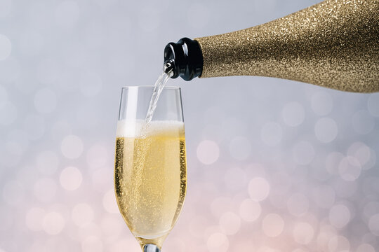 Golden sparkling wine being poured into a champagne flute, celebrating a festive occasion with glowing bokeh background evoking a sense of luxury and elegance