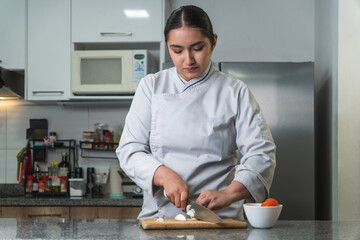 Latin chef cutting onions on wooden board in kitchen