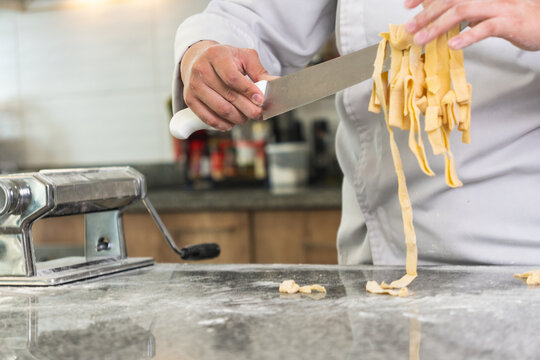Chef cutting fresh pasta with knife after using pasta machine