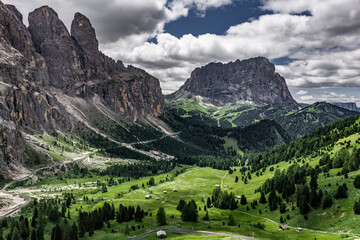  Majestic Sassolungo Langkofel massif towering over the lush green forests of Val Gardena in the...