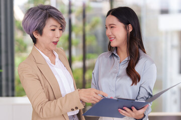 Experienced Asian business leader mentors young professional discussing corporate strategy...