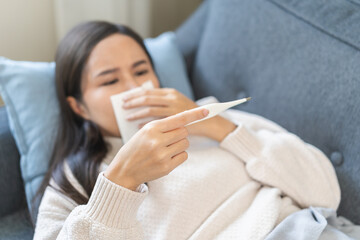 Sick, influenza asian young woman tired have fever, sneeze and blow nose, holding thermometer for...