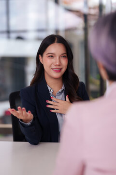 Young Asian professional woman attends job interview in office explaining answers to questions demonstrating confidence for career opportunity