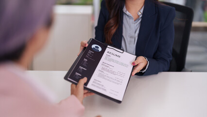 Professional recruiter hands job application resume to adult candidate office setting formal...