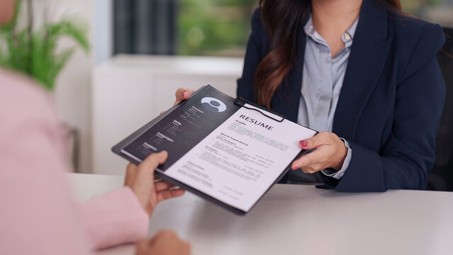 Professional adult Asian woman recruiter receives job application resume from a candidate in an office setting for interview or hiring process