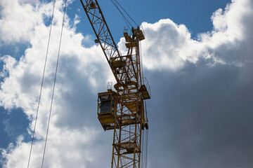 Construction crane towering against a backdrop of dramatic clouds at midday