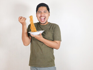Handsome Asian man holding noodles with a fork while shouting and getting angry. Eating lunch...
