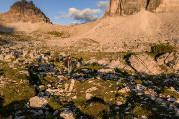 Hikers exploring rocky trails at the foot of Tre Cime di Lavaredo during golden hour, Dolomites,...