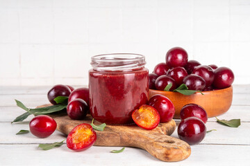 Cherry plum jam in small jar. Homemade autumn red cherry plum marmalade confiture with fresh...