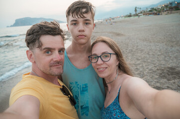 Happy family taking a photo on a beach at the sea in Alanya city, Turkey. Travelling or vacation concept