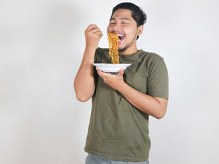 Handsome Asian man enjoying noodles with a fork. Eating lunch concept. Isolated white background