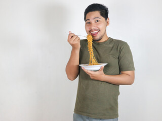 happy Handsome Asian man enjoying fried noodles with a fork. Eating lunch concept. Isolated white...