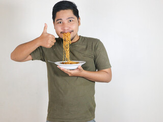 Handsome Asian man enjoying noodles, with the noodles still in his mouth, and giving a thumbs up. eating lunch concept. isolated white background