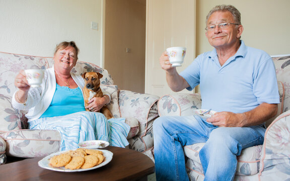Retirement: Tea and Biscuits. A senior couple enjoying a mid-day break with their pet dog. to From a series of related images with a retired couple.