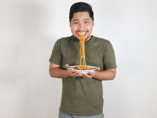 Handsome Asian man enjoying noodles, with the noodles still in his mouth. Eating lunch concept. Isolated white background