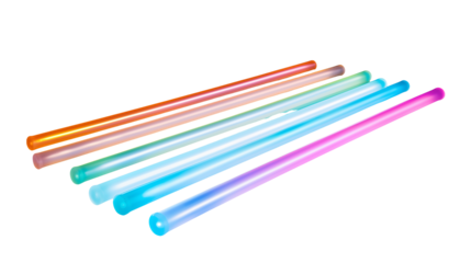 A close up view of several colorful glow sticks lying diagonally on a transparent background surface