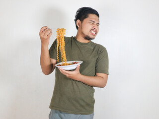 handsome asian man refuses to eat noodles by turning his face away from the noodles he is holding. eating lunch concept. isolated white background