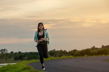 A plump young woman is exercising by jogging for better health during sunset.