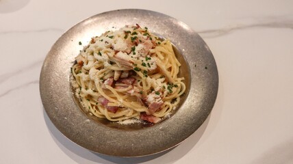 close up of creamy Carbonara spaghetti pasta with bacon and ham on a steel plate with copy space
