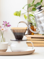 Barista pouring hot water into coffee filter with modern kettle
