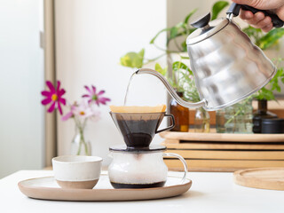 Barista pouring hot water into coffee filter with modern kettle