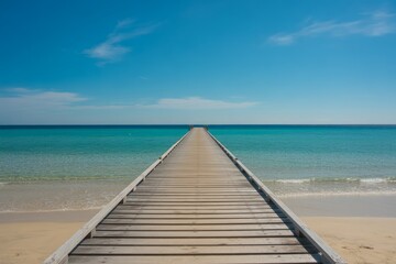 Obraz premium Wooden pier stretching into turquoise ocean under blue sky