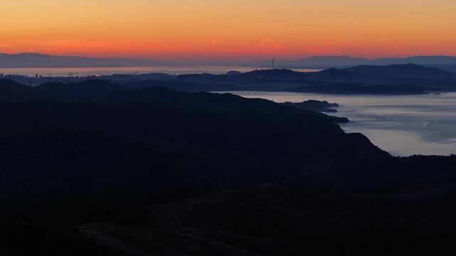 Aerial view of the iconic Sutro Tower standing tall amidst the cityscape, as a fiery sunset casts a warm glow over San Francisco, California, United States.