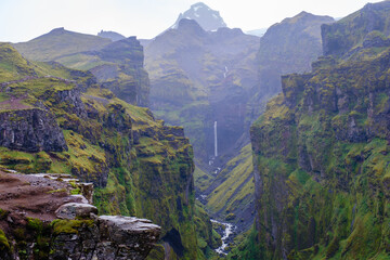 Majestic cliffs envelop Mulagljufur Canyon in Iceland, showcasing vibrant green landscapes and a...