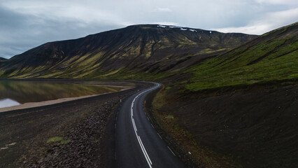 A winding road along Icelands coast offers breathtaking views of majestic mountains and calm waters.