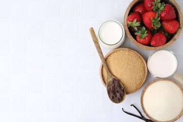 Different ingredients for panna cotta. Milk, sugar, vanilla, chocolate and strawberries on white tiled table, flat lay. Space for text