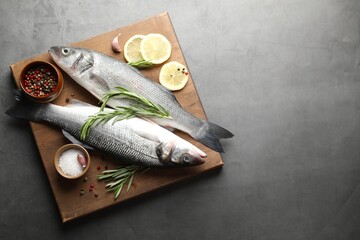 Fresh raw seabass fish with spices on grey table, top view and space for text. Seafood delicacies