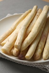 Raw white asparagus spears on grey textured table, closeup