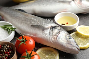 Fresh raw seabass with spices on grey table, closeup. Fish and seafood delicacies