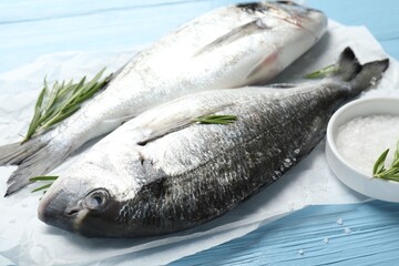 Fresh raw dourade with spices on blue wooden table, closeup. Fish and seafood delicacies