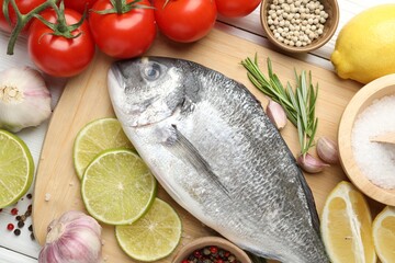 Fresh raw dourade with spices on white wooden table, flat lay. Fish and seafood delicacies