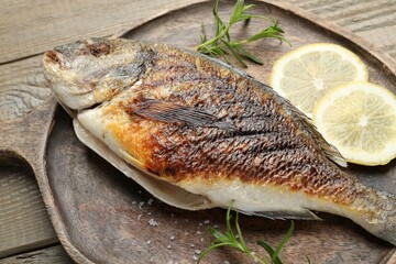 Tasty roasted dorado fish and spices on wooden table, closeup. Homemade seafood dish