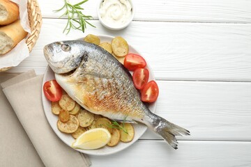 Homemade seafood dish. Tasty roasted dorado fish served with vegetables and sauce on white wooden table, flat lay. Space for text