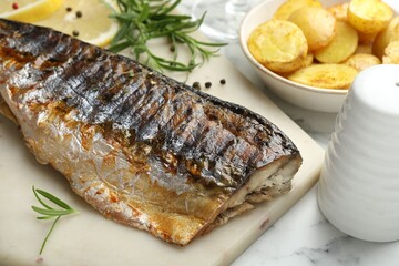 Tasty roasted mackerel with spices and potatoes on white marble table, closeup. Homemade seafood dish