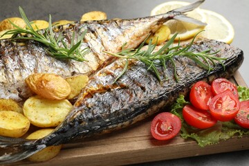 Tasty roasted mackerels with spices and vegetables on table, closeup. Homemade seafood dish