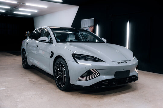 Front view of BYD Seal electric sedan in silver paint inside professional detailing studio &ndash; modern automotive lighting setup highlighting smooth body lines, futuristic headlights and glossy finish