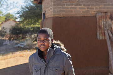 Africa village, single young african woman , walking outdoors in the yard, shack in the back